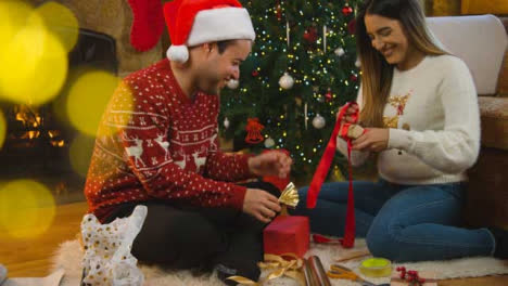 Weitschuss-Eines-Fröhlichen-Jungen-Paares,-Das-Zusammen-Weihnachtsgeschenke-Einpackt