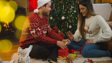 Wide-Shot-of-a-Young-Woman-Playfully-Disapproving-of-Boyfriends-Christmas-Gift-Wrapping