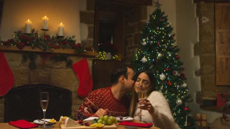 Sliding-Medium-Shot-Approaching-Young-Man-Kissing-His-Girlfriends-Cheek-During-Christmas