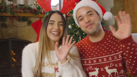 Young-Couple-Waving-and-Talking-to-Camera-During-Christmas-Video-Call
