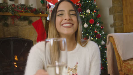 Junge-Frau,-Die-Während-Des-Weihnachtsvideoanrufs-Ein-Glas-Champagner-Anhebt-Und-Mit-Der-Kamera-Spricht