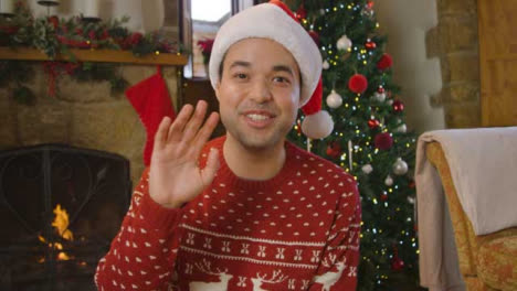 Young-Man-Waving-and-Talking-to-Camera-During-Christmas-Video-Call