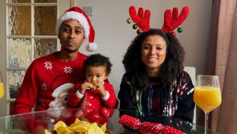 Young-Parents-with-Small-Child-Joining-Christmas-Video-Call-Waving-and-Talking-to-Camera