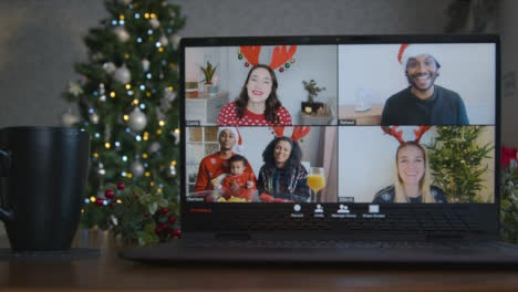 Sliding-Close-Up-Shot-of-4-Way-Split-Screen-Christmas-Themed-Video-Call-On-Laptop-Amongst-Friends