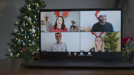 Schieben-Sie-Nahaufnahme-Eines-4-Wege-Split-Screen-Gruppenvideoanrufs-Mit-Weihnachtsmotiv-Auf-Dem-Laptop-Unter-Freunden