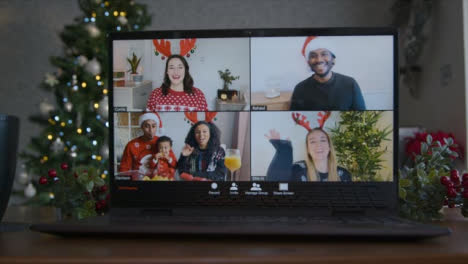 Close-Up-Shot-of-4-Way-Split-Screen-Christmas-Themed-Video-Call-On-Laptop-Amongst-Friends