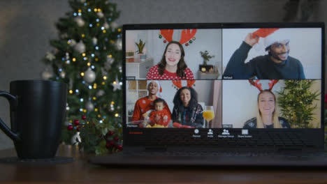 Sliding-Close-Up-Shot-of-a-4-Way-Split-Screen-Christmas-Themed-Video-Call-On-Laptop-Amongst-Friends