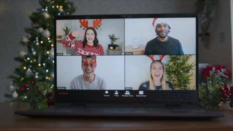 Close-Up-Shot-of-4-Way-Split-Screen-Christmas-Themed-Group-Video-Call-On-Laptop-Amongst-Friends