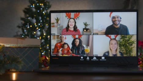 Sliding-Close-Up-Shot-of-4-Way-Split-Screen-Christmas-Group-Video-Call-Amongst-Friends-On-Laptop