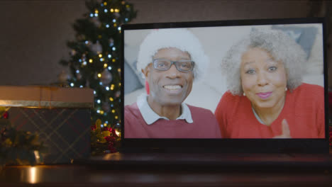 Sliding-Close-Up-Shot-of-Senior-Couple-During-Video-Call-On-Laptop-Screen-In-Christmas-Environment