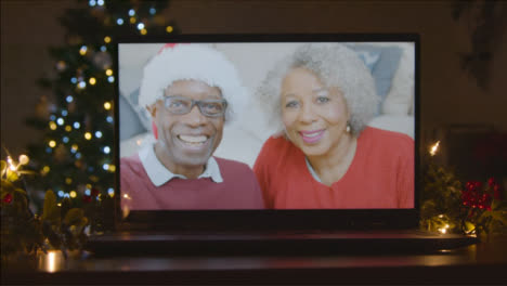 Sliding-Shot-Approaching-Senior-Couple-During-Video-Call-On-Laptop-Screen-In-Christmas-Environment