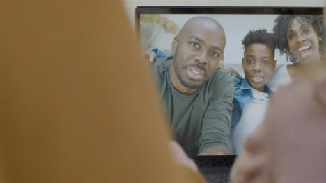 Sliding-Over-the-Shoulder-Shot-of-People-Waving-at-Family-On-Video-Call-