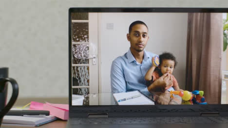 Sliding-Medium-Shot-of-Laptop-Screen-with-Working-Father-and-Baby-On-Video-Call