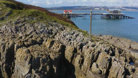 Drone-Shot-Passing-Over-Rocks-Revealing-Mumbles-Pier-01