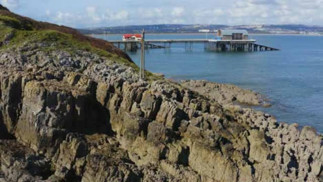 Drone-Shot-Passing-Over-Rocks-Revealing-Mumbles-Pier-02