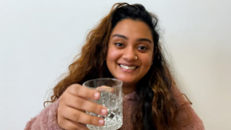 Una-Joven-Estudiante-Hablando-Y-Levantando-Un-Vaso-Directamente-A-La-Cámara.