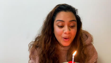 Eine-Junge-Studentin-Bläst-Während-Eines-Videoanrufs-Eine-Kerze-Auf-Einer-Geburtstagstorte-Aus