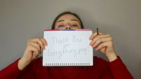 Female-Young-Student-Holding-Up-Thank-You-Sign-During-Video-Lecture