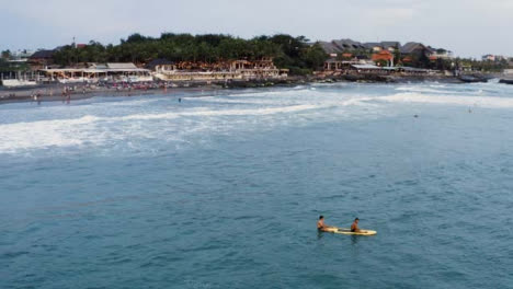 Drone-Shot-Orbiting-Two-People-Sitting-On-Surf-Board-In-Ocean
