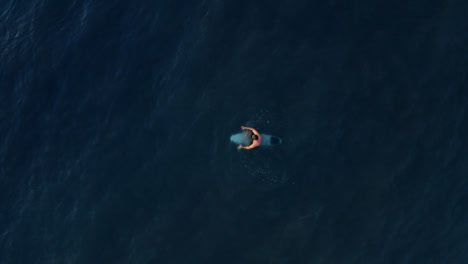 Drone-Shot-Looking-Down-On-Surfer-In-Ocean-Waiting-for-Wave-