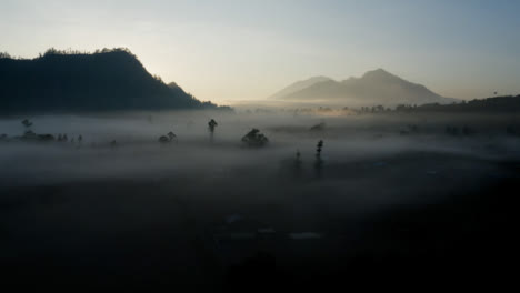 Drone-Shot-Flying-Over-Low-Hanging-Mist-Around-Mount-Batur-Volcano