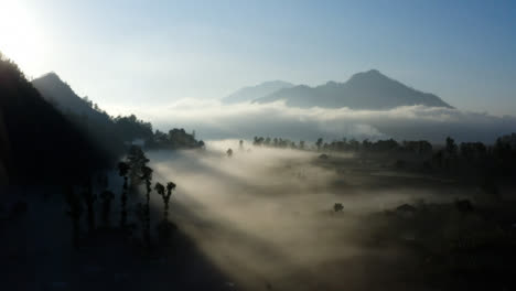 Drone-Shot-Passing-Over-Low-Hanging-Fog-Surrounding-Mount-Batur