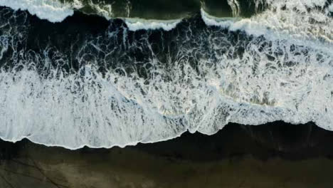 Drone-Shot-Looking-Down-On-Waves-at-Pigstone-Black-Sand-Beach