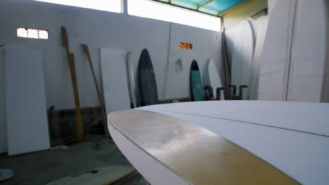 Tiro-De-Seguimiento-De-Mano-A-Lo-Largo-De-La-Tabla-De-Surf-En-El-Taller