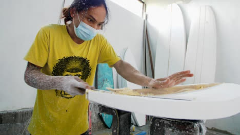 Handheld-Wide-Shot-of-Surfboard-Shaper-Cutting-Wood-Away-from-Polystyrene-Board