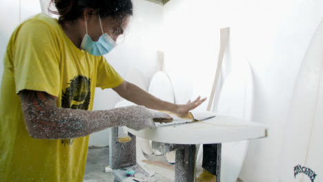 Handheld-Wide-Shot-of-Surfboard-Shaper-Cutting-Wood-Away-from-a-Polystyrene-Board