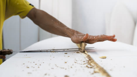 Handheld-Close-Up-Shot-of-Surfboard-Shaper-Cutting-Wood-Away-from-Polystyrene-Board