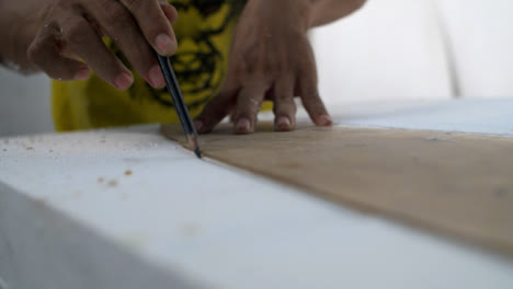 Primer-Plano-De-Mano-De-Surboard-Shaper-Trazado-Sobre-Placa-De-Poliestireno