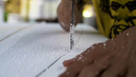 Handheld-Close-Up-Shot-of-a-Saw-Cutting-Through-Polystyrene-Surfboard
