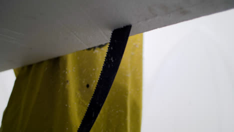 Handheld-Close-Up-Shot-of-a-Saw-Cutting-Through-a-Polystyrene-Surfboard