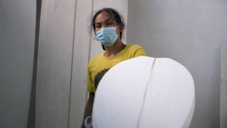 Handheld-Long-Shot-of-a-Surfboard-Shaper-Using-a-Power-Tool-On-Polystyrene-Surfboard