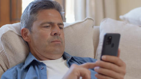 Nahaufnahme-Eines-Mannes-Mittleren-Alters,-Der-Mit-Smartphone-Auf-Dem-Sofa-Ruht