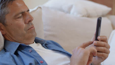 Close-Up-Shot-of-a-Middle-Aged-Man-Slouched-On-Sofa-Using-Smartphone-
