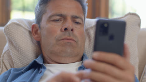 Nahaufnahme-Eines-Mannes-Mittleren-Alters,-Der-Mit-Smartphone-Auf-Einem-Sofa-Sitzt