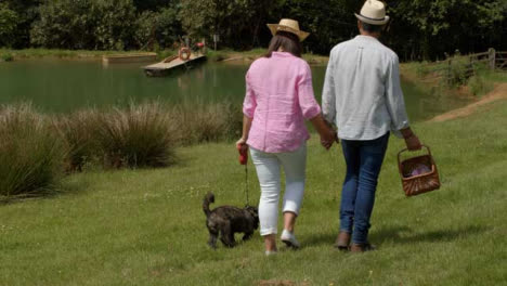 Tracking-Shot-Following-Middle-Aged-Couple-Walking-Dog-Next-to-Scenic-Lake