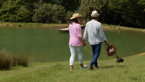 Tracking-Shot-Following-Middle-Aged-Couple-Walking-a-Dog-Next-to-Scenic-Lake
