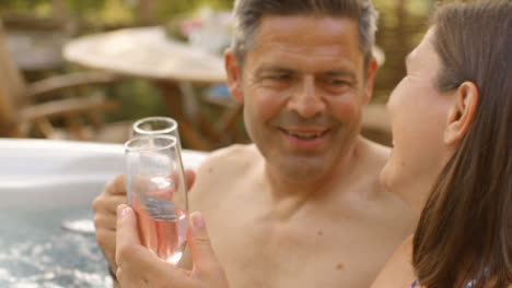 Pull-Focus-Shot-of-Middle-Aged-Couple-Enjoying-Champagne-In-Hot-Tub