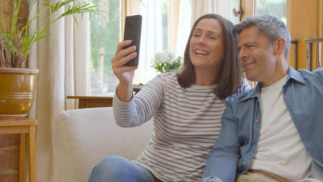 Mittlere-Aufnahme-Eines-Paares-Mittleren-Alters,-Das-Smartphone-Für-Videoanrufe-Verwendet