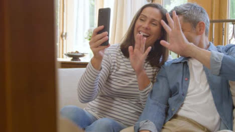 Sliding-Shot-of-Middle-Aged-Couple-Using-Smartphone-for-Video-Call