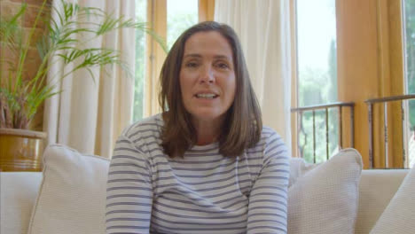 POV-Shot-of-Middle-Aged-Woman-Waving-Hello-and-Talking-to-Camera-During-Video-Call