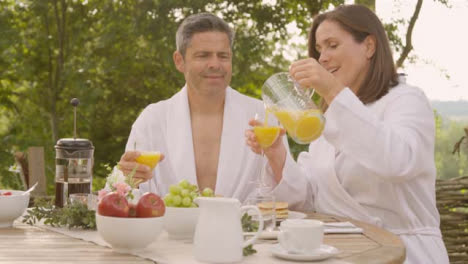 Weitwinkelaufnahme-Eines-Paares-Mittleren-Alters,-Das-Beim-Frühstück-Gläser-Zusammenbringt?