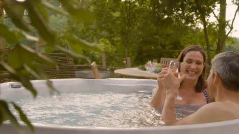 Wide-Shot-of-Middle-Aged-Woman-Drinking-Champagne-In-Hot-Tub-with-Husband