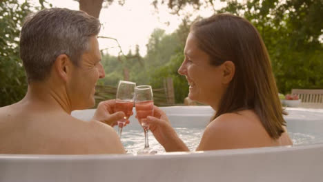 Close-Up-Shot-of-Middle-Aged-Couple-Drinking-Champagne-In-Hot-Tub-
