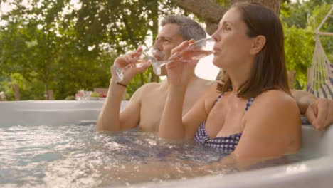 Medium-Shot-of-Middle-Aged-Couple-Drinking-Champagne-In-Hot-Tub-