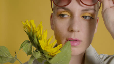 Close-Up-Shot-of-Model-Posing-with-Sunflower-and-Sunglasses-for-Fashion-Shoot