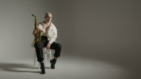 Weitwinkelaufnahme-Eines-Models,-Das-Mit-Saxophon-Vor-Grauem-Hintergrund-Posiert